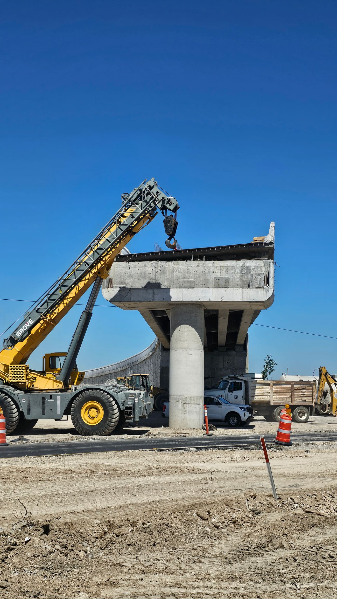 Grúa realizando el montaje de una trabe prefabricada de concreto sobre una pila de puente en construcción