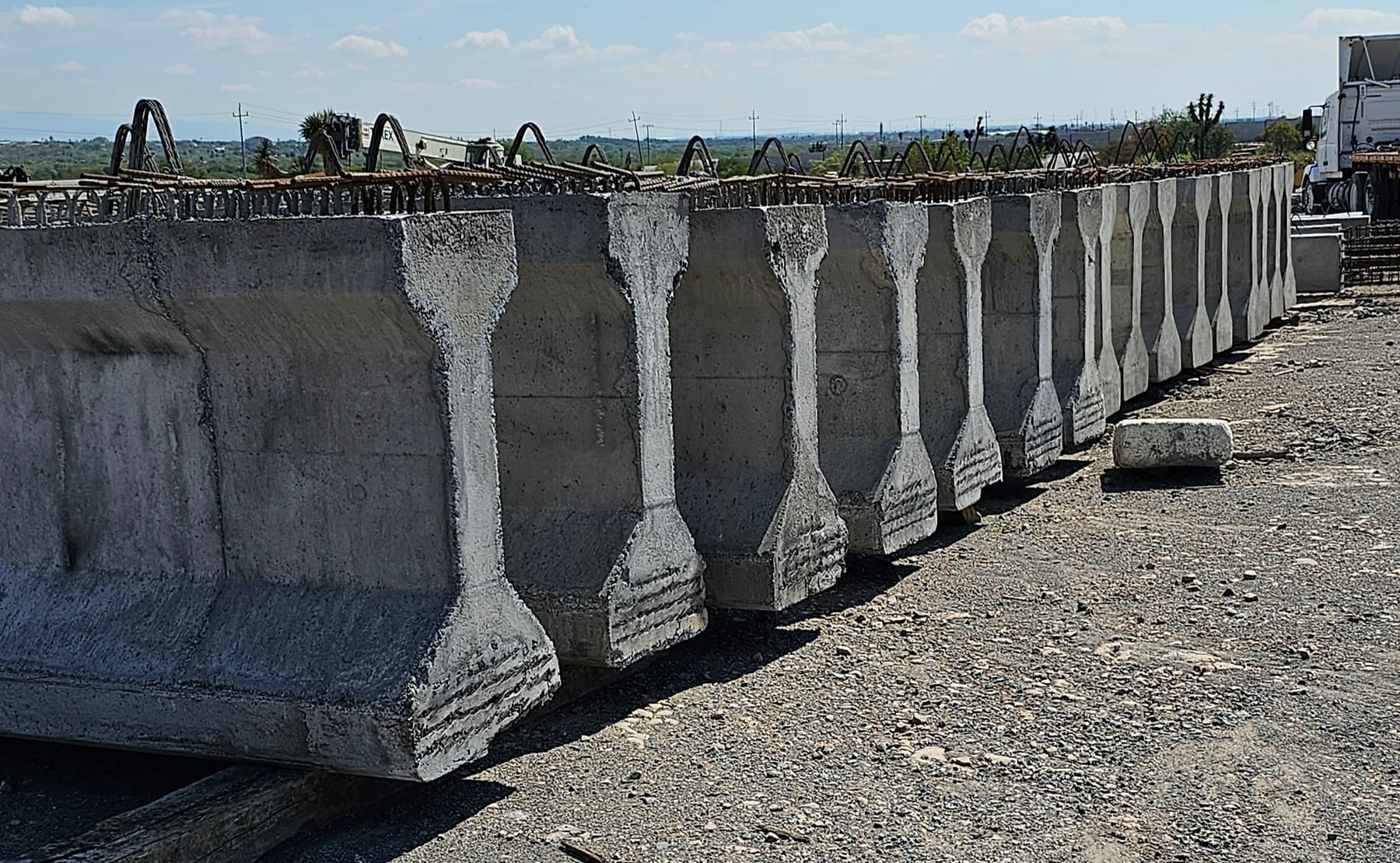 Fila de trabes prefabricadas de concreto almacenadas en patio, listas para su transporte
